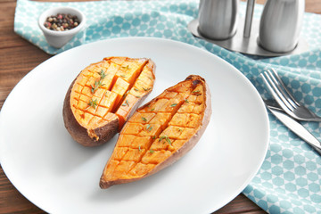 Plate with baked sweet potato on table