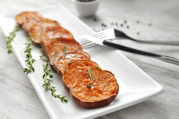 Plate with baked sweet potato on table