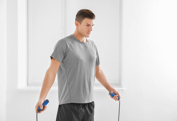 Young man with jumping rope indoors