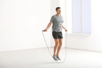 Young man skipping rope indoors - obrazy, fototapety, plakaty