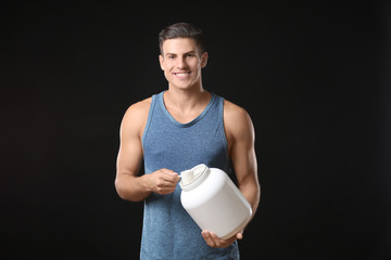Young man holding white jar with protein powder on black background
