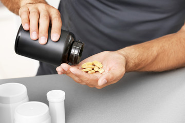 Man with protein pills and bottle, closeup