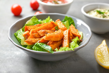 Plate with sweet potato fries on table