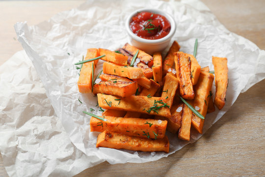 Parchment with sweet potato fries on table