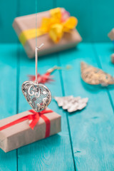Christmas decoration heart hanging by a thread in the background gifts. Wooden planks sea green in the background.
