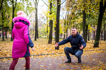 Fototapeta premium he child runs to meet his father.. A little girl runs through the autumn park to her father's arms. family walking in the forest on a sunny autumn day father and daughter enjoying time together 