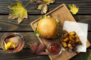 burger with potato on wooden plate with cocktail on wooden table