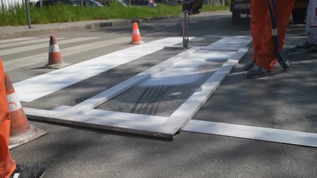 Painting the pedestrian crossing, repairing the road and painting lines, traffic in the background