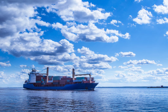 The ship is carrying containers. A merchant ship in the background of clouds.