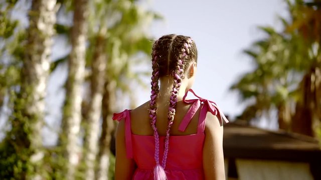 A teenager with pigtails on her head goes straight through the park, then the girl turns around and looks playfully