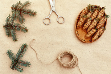 Fototapeta na wymiar Handmade Christmas gifts, and everything necessary for them, on the Background of Kraft paper, scissors, pine cones and jute cord. The view from the top. The concept of simplicity