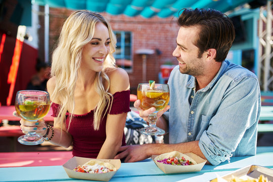 attractive romantic couple holding beers at mexican restaurant about to eat tacos
