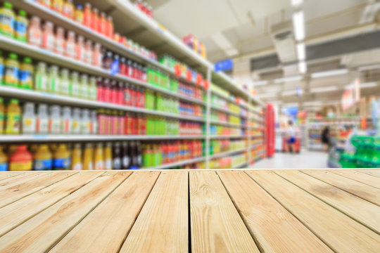Empty wooden table and supermarket blurred drink background