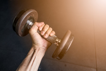 Hand holding dumbbell in fitness gym.