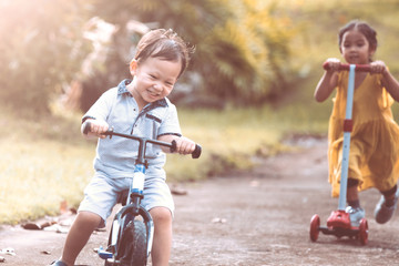 Cute asian little child boy having fun to ride his balance bike in the park in vintage color tone