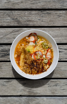 Spicy egg noodle soup with roasted pork on wood table background, outdoor day light
