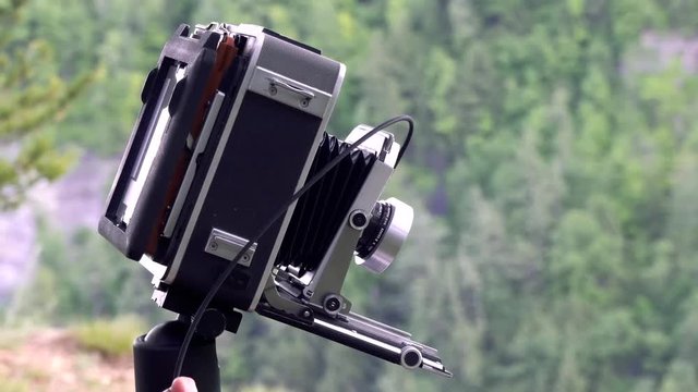 A photographer makes adjustments to a large format camera during landscape photography.