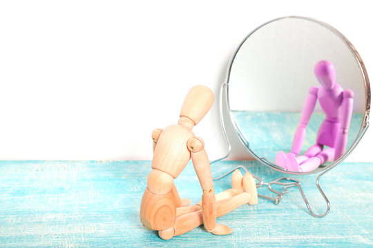 Wooden person Gestalta in front of the mirror