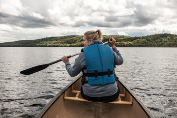 Girl canoeing with Canoe on the lake of two rivers in the algonquin national park in Ontario Canada on sunny cloudy day