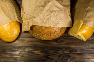 Assortment of bread packed in paper on wooden table