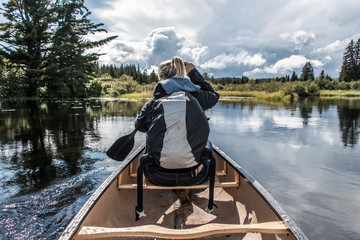 Girl canoeing with Canoe on the lake of two rivers in the algonquin national park in Ontario Canada on sunny cloudy day - obrazy, fototapety, plakaty