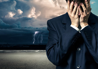 Businessman in despair on stormy sky