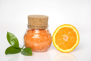 bath salt with  extract of orange. Orange sea salt in a glass jar and orange in a cut on a light background. Organic Citrus Natural Cosmetics