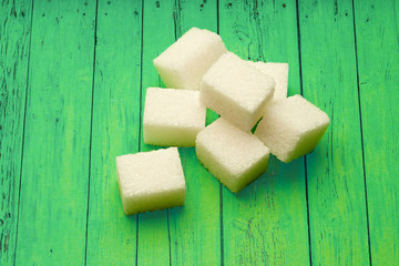 Sugar cubes on green wooden background