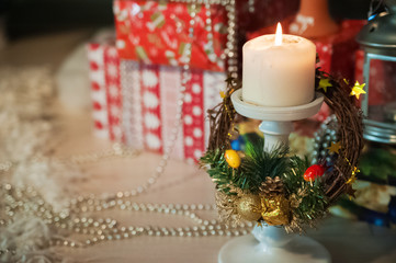 Many lit candles stand on the table on the background of the New Year tree. Background for your text.  Many gifts under the New Year tree. Set of multi-colored gifts