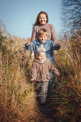Naklejka na ściany i meble Happy woman and two sons in a field in an autumn