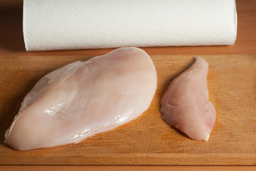 raw chicken fillets on wooden cutting board, top view.