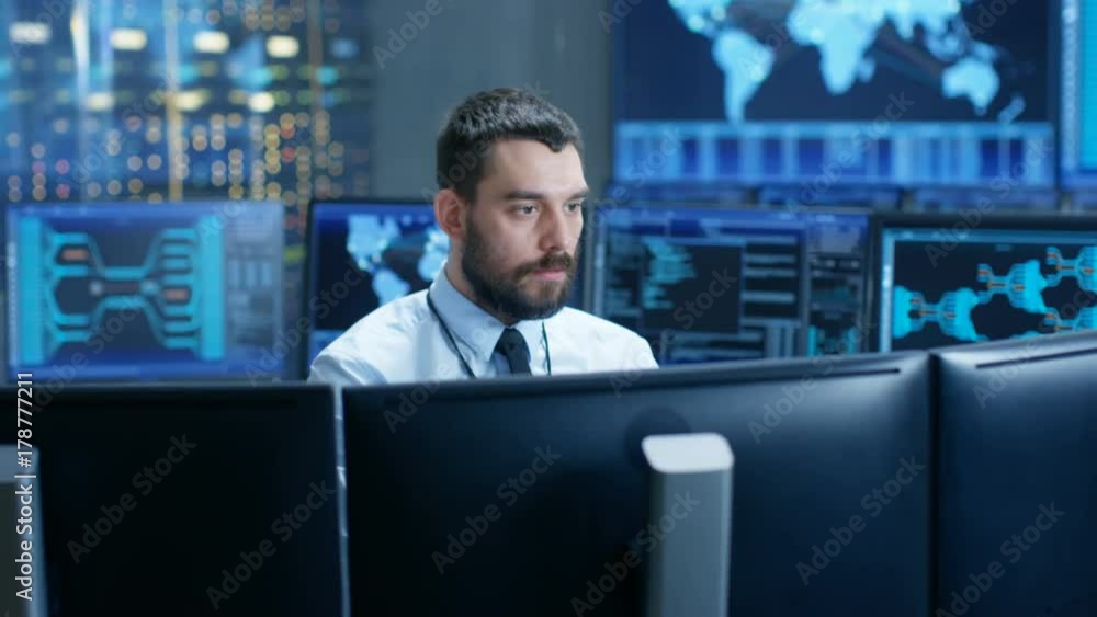 Fototapete In the System Control Center Operator Working Surrounded by Displays Showing Relevant Data. In the Background Data with Interactive Map. Shot on RED EPIC-W 8K Helium Cinema Camera.