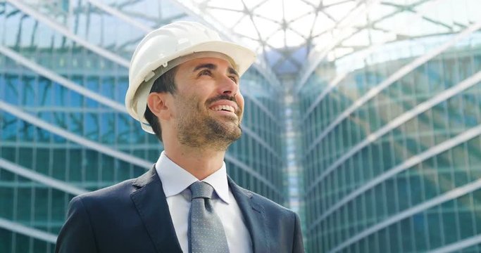 An engineer with a security helmsman, looks proud of the success of his construction project. Concept of: engineering, buildings, business, dream, success