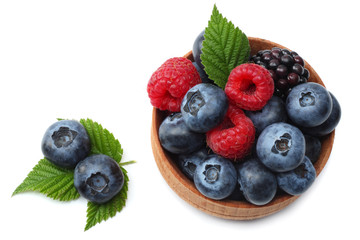mix of blueberries, blackberries, raspberries in wooden bowl isolated on white background. top view