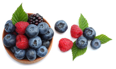 mix of blueberries, blackberries, raspberries in wooden bowl isolated on white background. top view