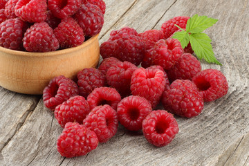ripe raspberries in wooden bowl on old wooden table background