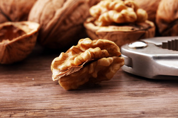 Walnut kernels and whole walnuts on brown wooden table.