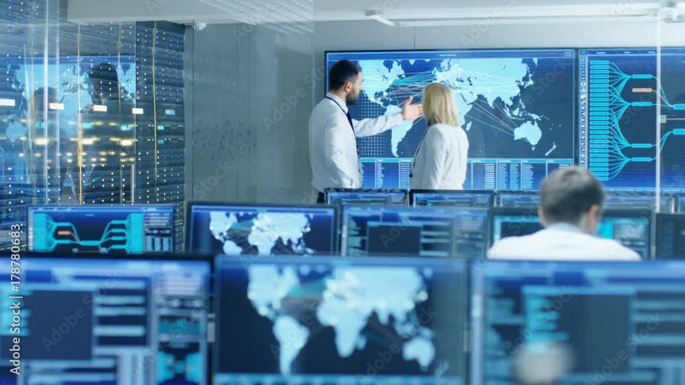 Poster In the System Monitoring Room Two Senior Operators Work on a Big Interactive Map. Facility is Full of Screens Showing Technical Data. Shot on RED EPIC-W 8K Helium Cinema Camera.