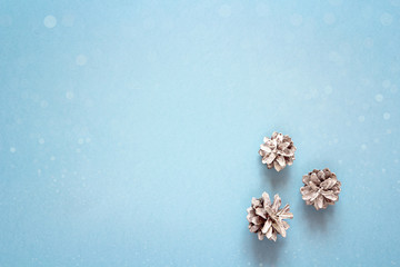 Snow painted pine cones on blue background. Copy space.