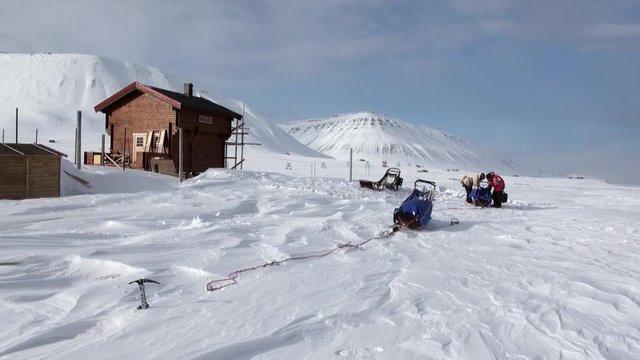 People on base of sled dogs husky Eskimo road of North Pole in Arctic. Way from airport Longyear to Pyramid Spitsbergen on background of glacier mountains Svalbard in Norway.