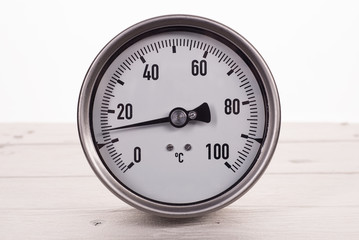 dial gauge thermometer on a white wooden background