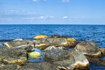 Fototapeta na wymiar Landscape of rocky seashore with blue calm waters in summer day as natural background