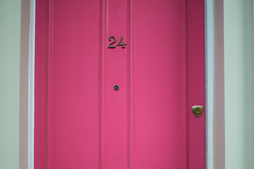 Door number 24 (twenty four). Metal plate on pink wooden door