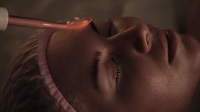 Beautiful woman has a electric darsonval massage procedure in a dark