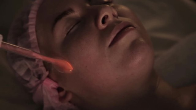 beautician does electric darsonval massage procedure for female client in a dark