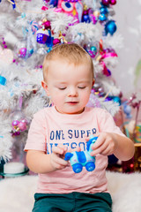 Little child plays before pink Christmas tree