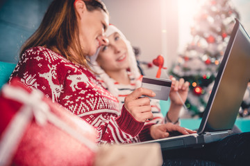Mother and daughter shopping online at home during christmas