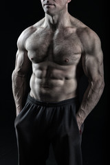 Fototapeta na wymiar Athletic bodybuilder pose in pants isolated on black background.