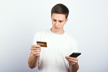 Portrait of a guy who holds a credit card and pays a mobile payment
