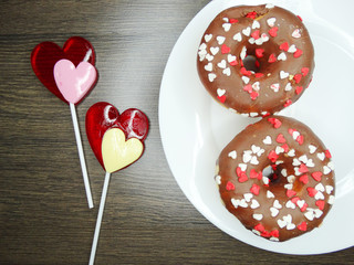 Fototapeta na wymiar heart lollipops and donuts sweet love valentine's day on wooden background